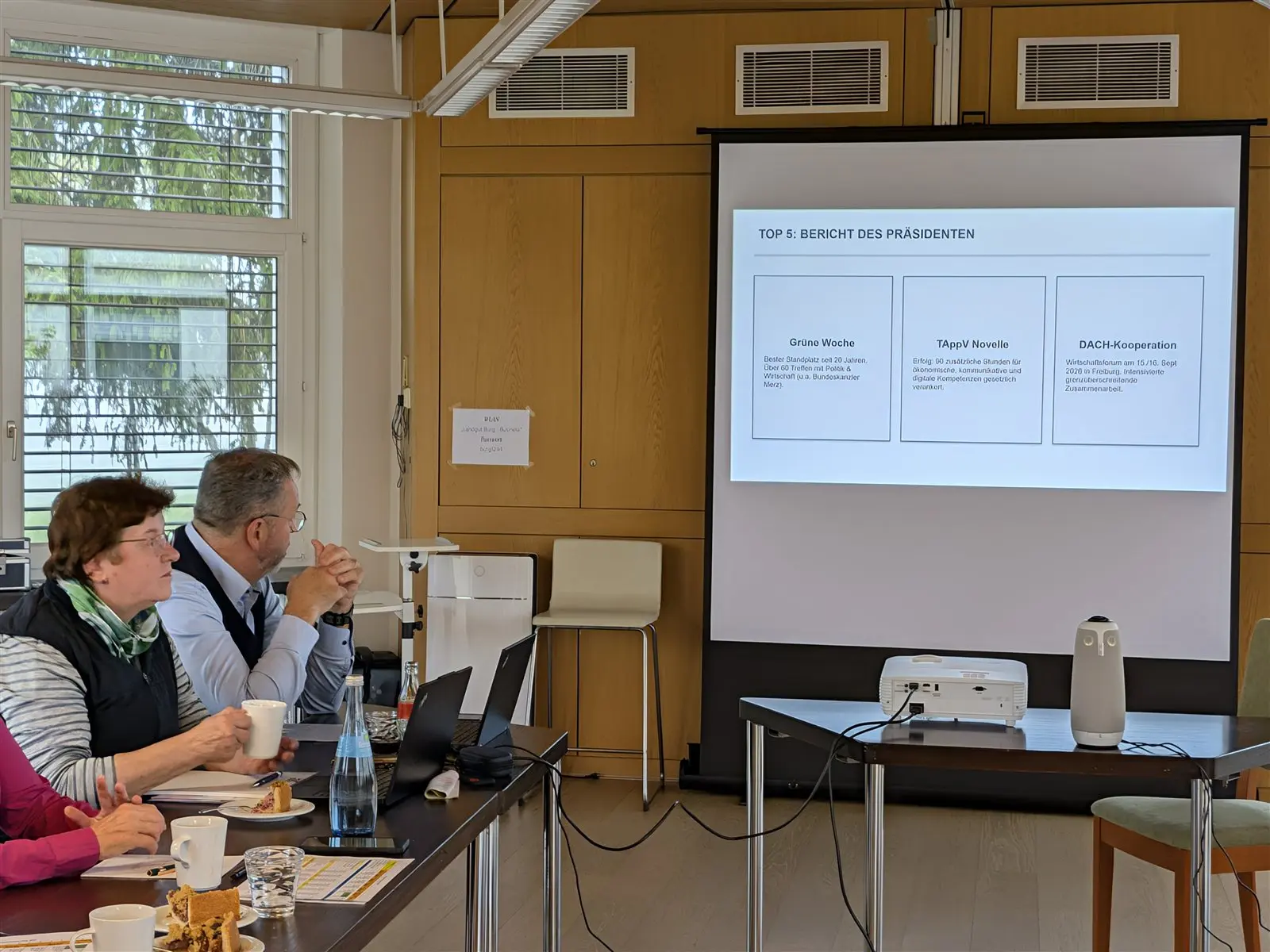 Zwei Teilnehmende verfolgen die Präsentation auf der Leinwand
